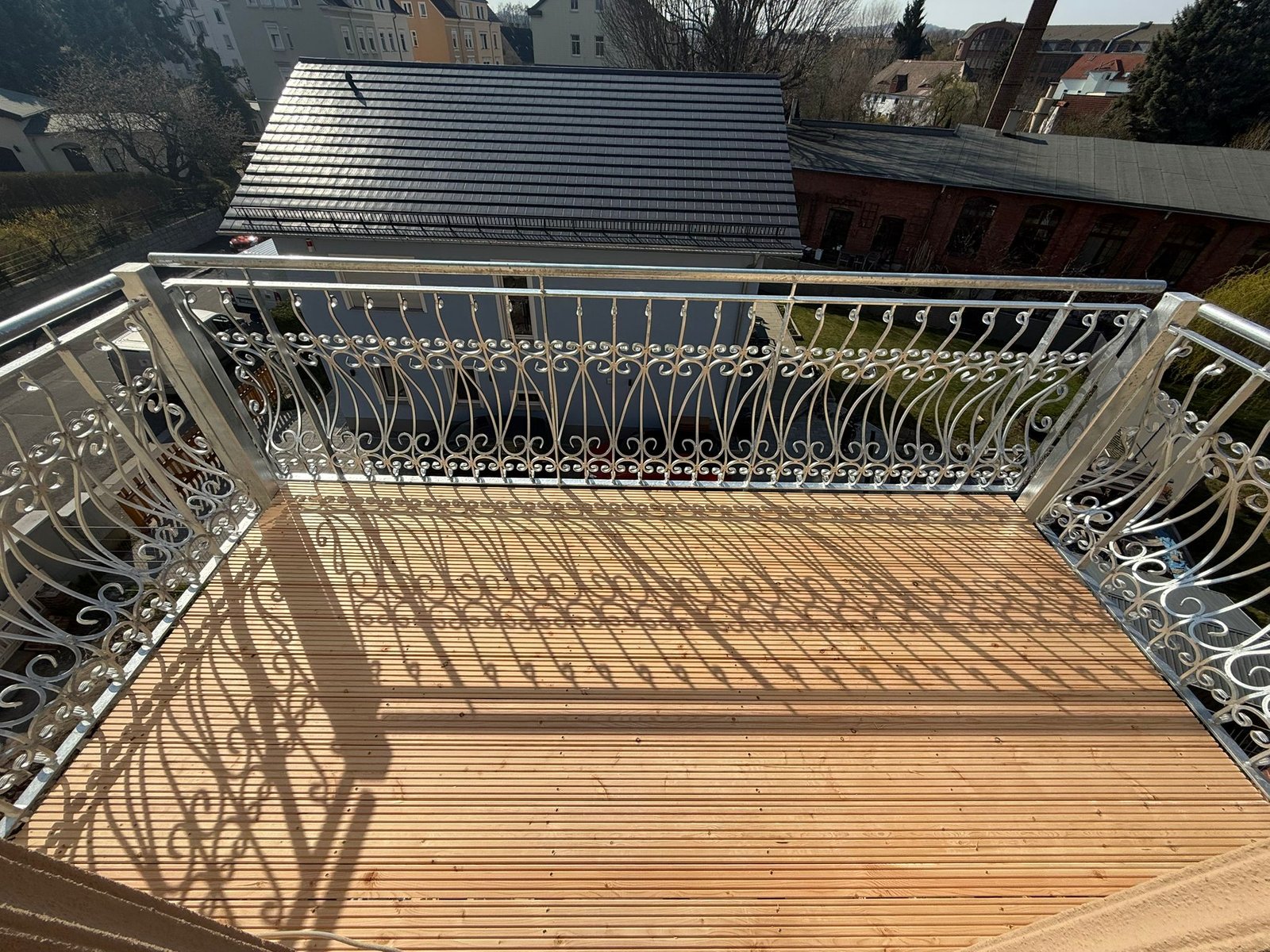 Blick über einen Balkon mit verzinktem Geländer und Holzbelag