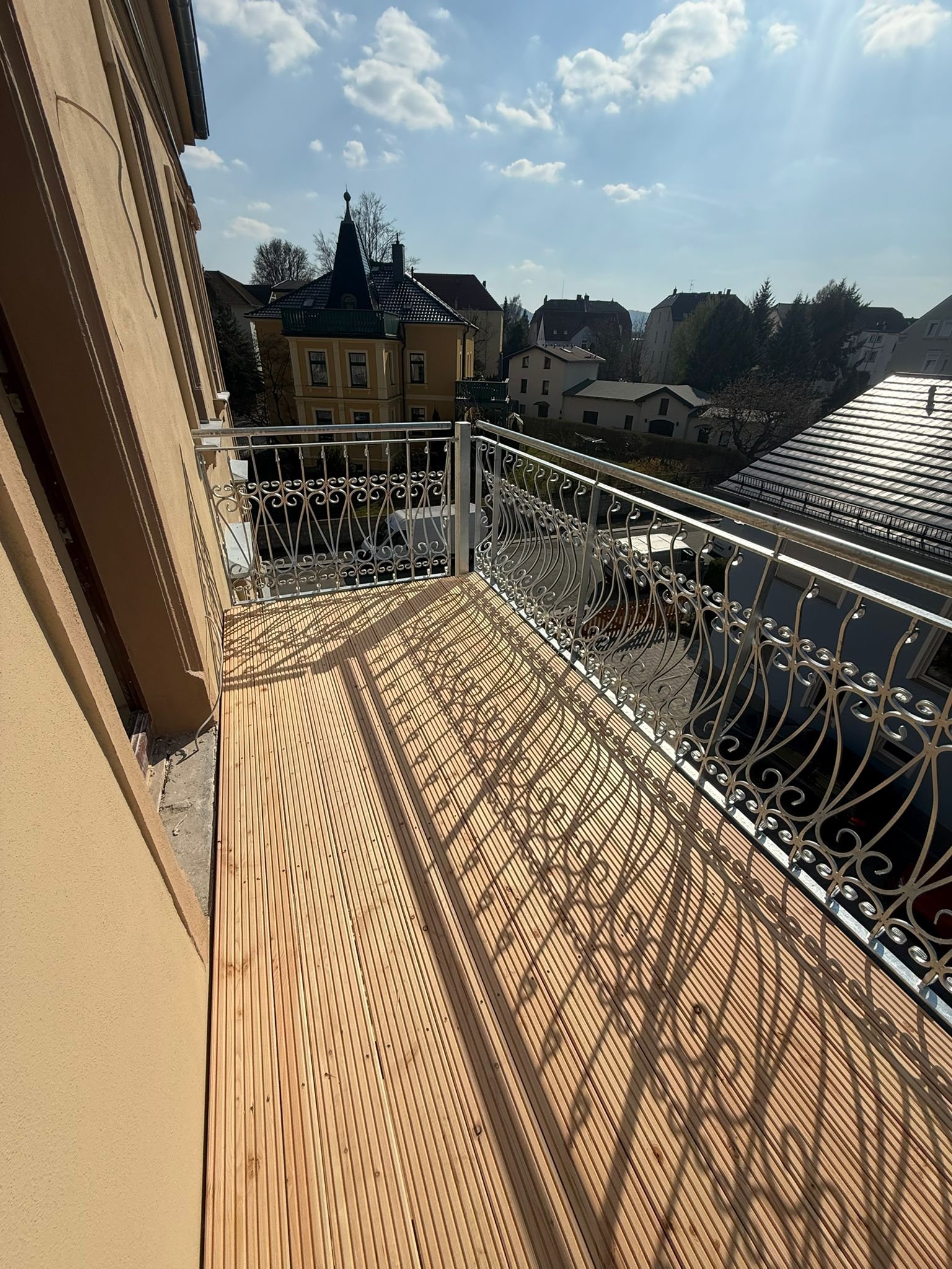 Balkonfläche mit Holzbelag und dekorativem Metallgeländer in Zittau
